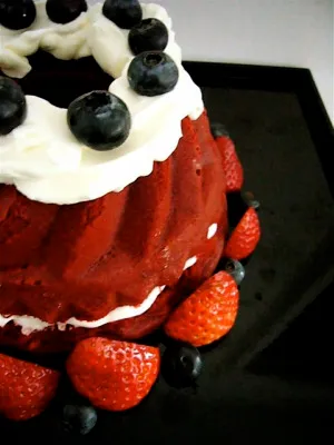 Red velvet cake topped with whipped cream, blueberries, and strawberries.