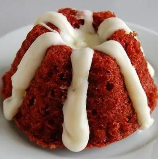 Red velvet cupcake with cream cheese icing on a white plate.