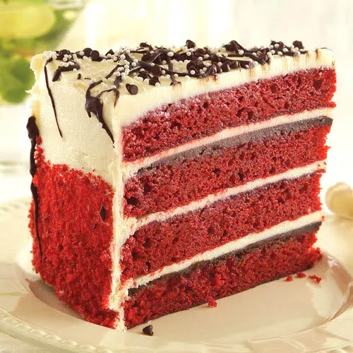 Red velvet cake slice with cream cheese frosting and chocolate shavings.