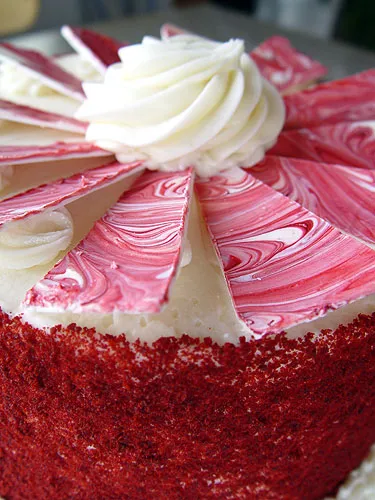 Red velvet cake with decorative frosting and swirled icing on top.
