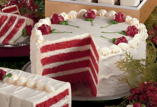 Red velvet cake with sliced portion and decorative roses on top.