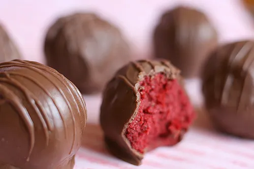 Chocolate truffles with a red filling, one partially bitten.