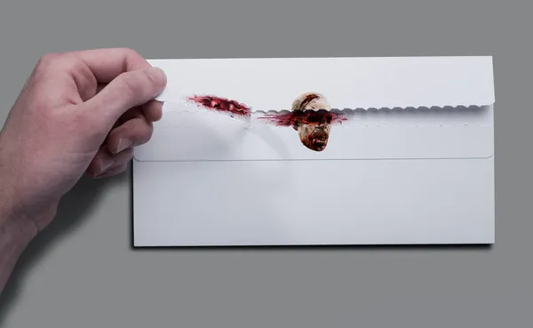 Hand holding a knife slicing through an envelope with a bloody mark.