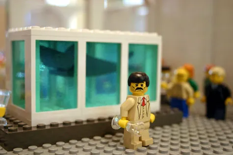 Lego figure in front of an aquarium display with a shark model.