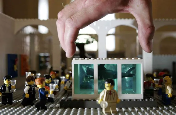 A hand placing a LEGO structure in a scene with miniature figurines.