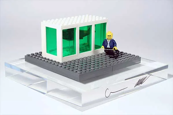 Lego architectural model with a figure sitting near a glass-like structure.