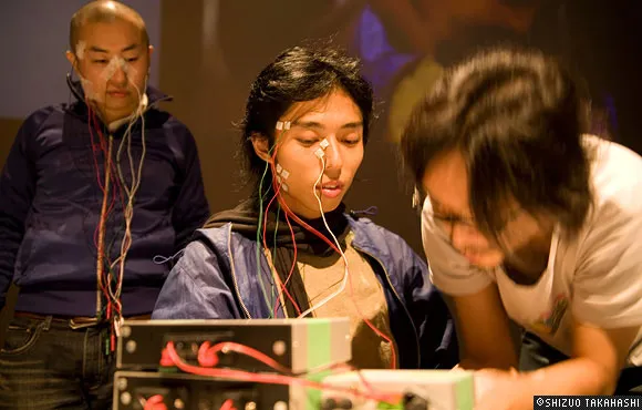 A group of individuals engaged in a technology-related project with wires and equipment.