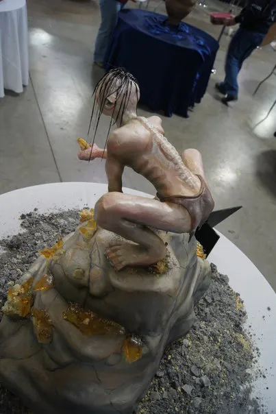 A detailed sculpture of a figure crouching on a textured base, surrounded by decorative elements.