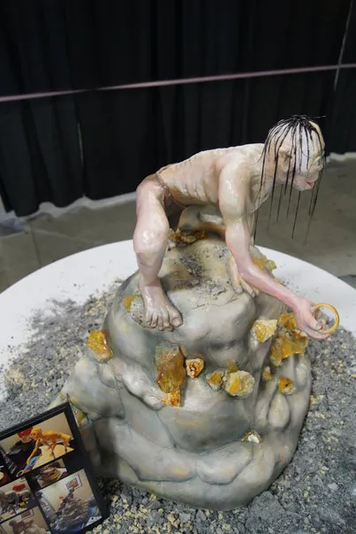 Artistic sculpture of a figure sitting on a rock surrounded by yellow elements.