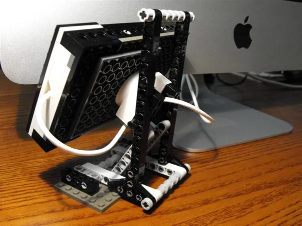 Lego stand for a computer monitor on a wooden desk.