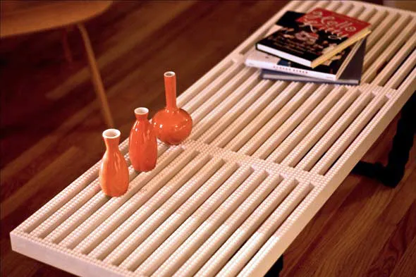 Modern coffee table with three orange vases and stacked books.