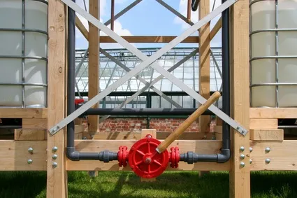 Water control valve on a wooden frame structure in a greenhouse setting.