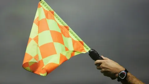 A person holding an orange and yellow checkered flag.