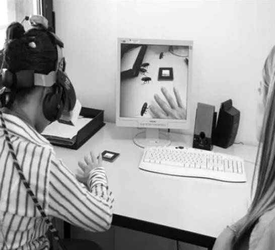 Person using virtual reality headset while interacting with a computer display.