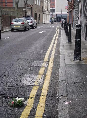 Empty city street with yellow lines and litter on the pavement.