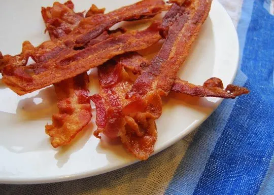 Crispy bacon strips on a white plate.