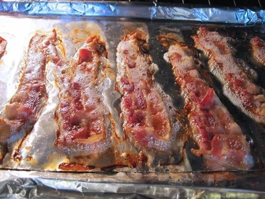 Crispy bacon strips baking on a tray.