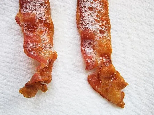Crispy cooked bacon on a white paper towel.