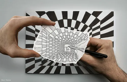 A hand drawing a spiral optical illusion on paper against a striped background.