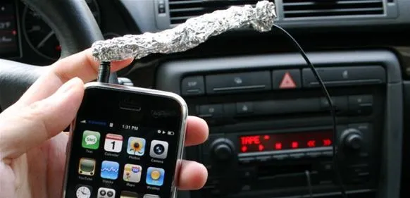 Smartphone with a makeshift antenna in a car dashboard.