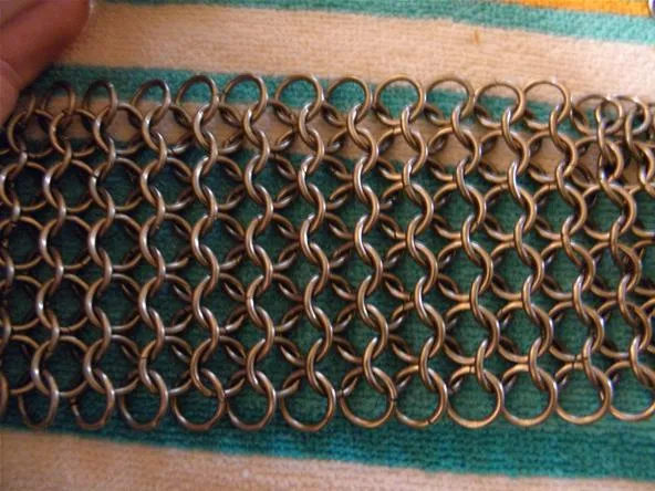 Metal chainmail pattern on a green and white background.