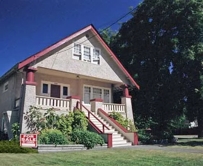 Bungalow-style house with a "For Sale" sign in the front yard.