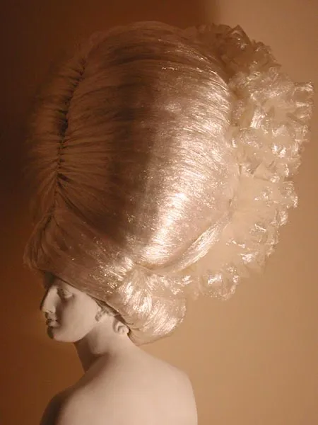 A mannequin with an oversized, sculptural wig styled in a vintage fashion.
