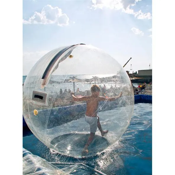 Child playing inside a transparent inflatable water bubble at the beach.