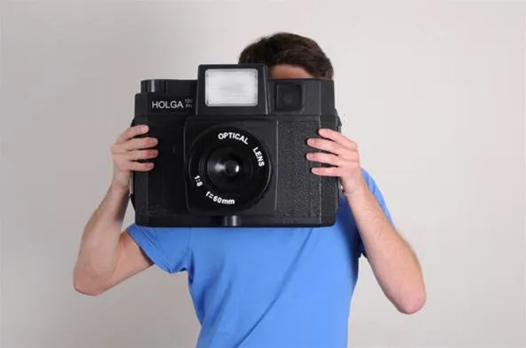 Person holding a large vintage camera in front of their face.