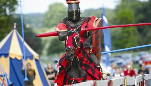 Knight in armor on horseback, participating in a jousting event.