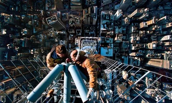 Construction workers at the top of a skyscraper in an urban environment.