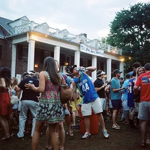 Outdoor gathering with a diverse group of people socializing at a venue with columns.