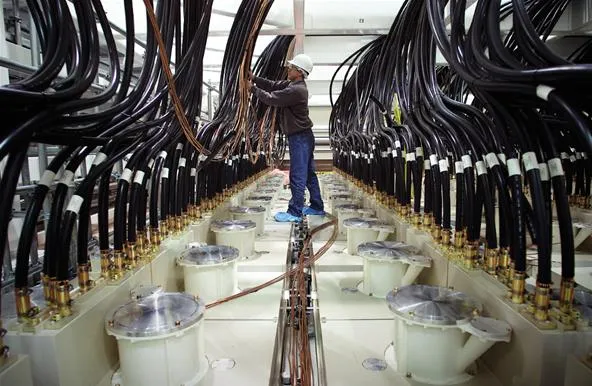 Worker inspecting machinery in a facility with complex piping systems.