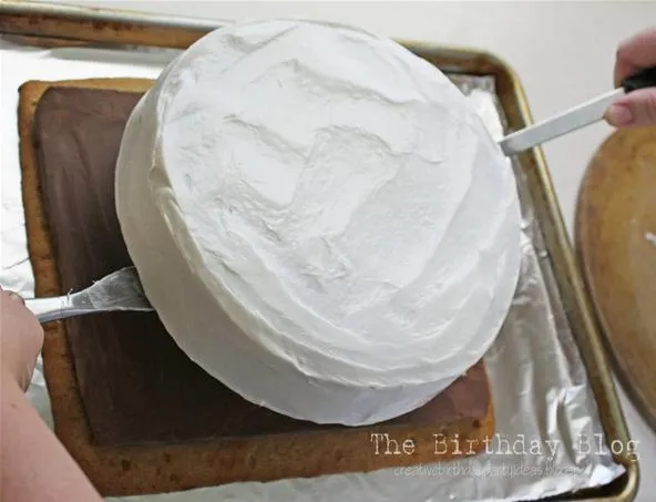 Cake being frosted with white icing.