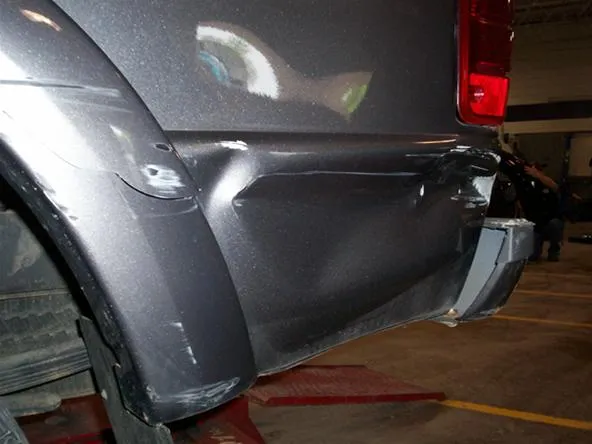 Damaged rear bumper of a gray vehicle.