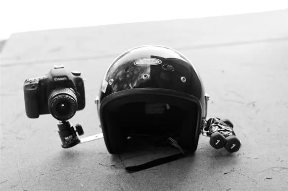 Camera and motorcycle helmet on a surface.