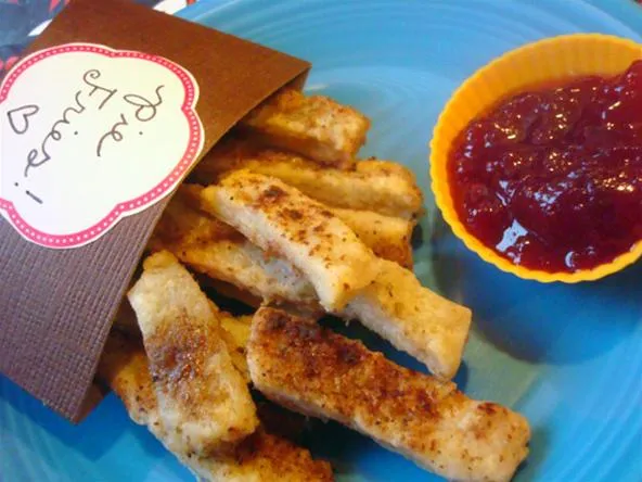 Fried food sticks served with a side of dipping sauce.