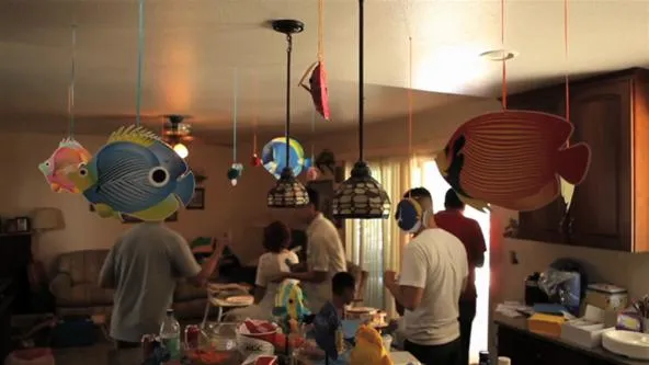 Decorative fish-themed decorations hanging from the ceiling in a lively gathering.