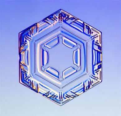Hexagonal ice crystal with intricate patterns against a blue background.