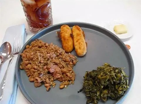 Plate of rice and beans, fried plantains, sautéed greens, and iced tea.