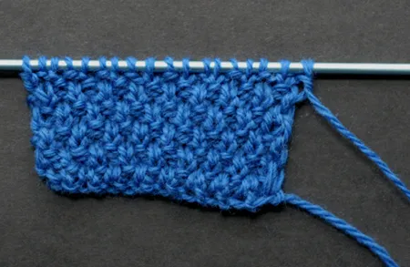 Blue knitted piece on a knitting needle.