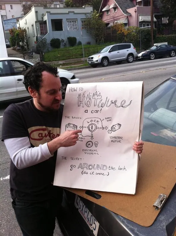 A man holding a large poster with hand-drawn diagrams and text.