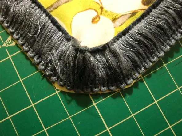 Close-up of a fabric edge with fringe on a patterned background.