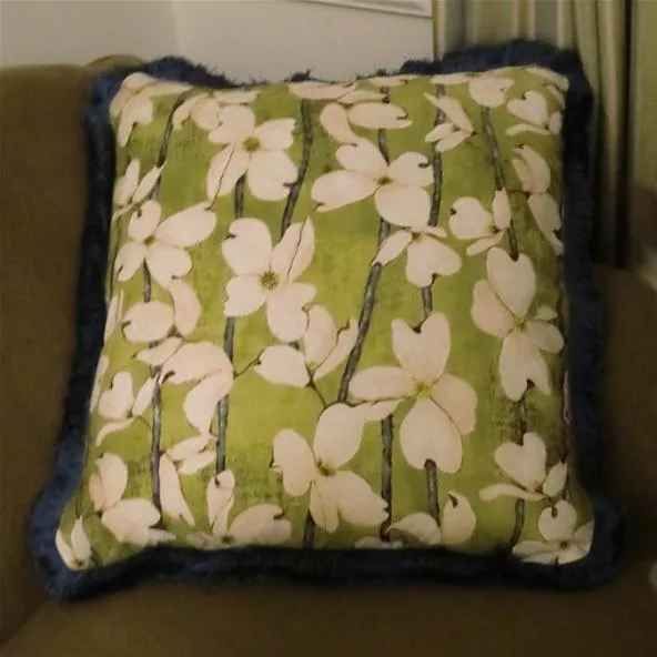 Decorative floral pillow on a green background.