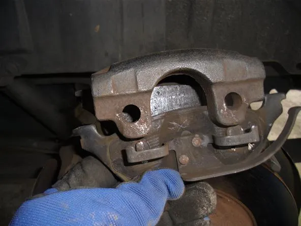 Brake caliper being inspected on a vehicle.