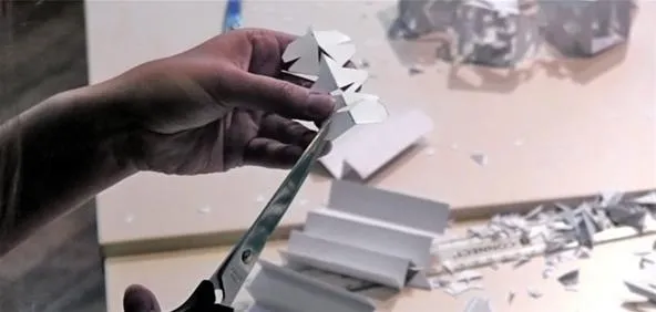 A person cutting paper with scissors, showcasing a craft or design project.