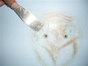 Applying putty to a wall surface with a putty knife.
