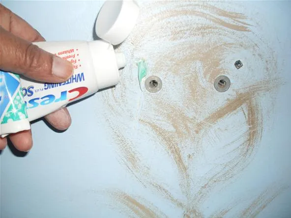 Person using toothpaste to create a drawing on a wall.