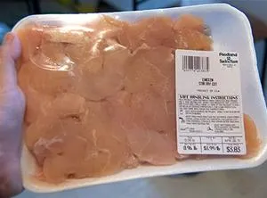 Raw chicken breast in packaging with nutritional information label.