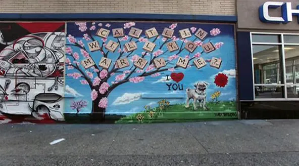 Colorful mural featuring a cherry blossom tree with the text "Call Me When You Are Broken" and an illustration of a dog, set against a sky with clouds.